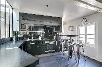 spacious kitchen with a small kitchen counter with four seats in Paris luxury apartment