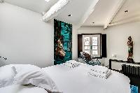 first bedroom in aqua, white and gray hues, furnished with a king-size bed with built-in shelves, an