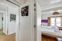 second bedroom in purple and fuschia hues furnished with two single beds, a few chairs, a desk, and 