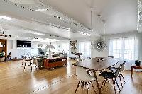 dining area with a long wooden table and six modern chairs in Paris luxury apartment