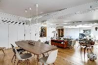 dining area with a long wooden table and six modern chairs in Paris luxury apartment