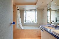 an en-suite bathroom with a toilet, a sink, a built-in cabinet, a mirror, and a bathtub in a 3-bedro