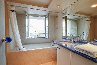 an en-suite bathroom with a toilet, a sink, a built-in cabinet, a mirror, and a bathtub in a 3-bedro