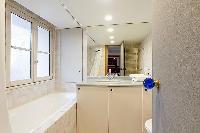 an en-suite bathroom with a toilet, a sink, a built-in cabinet, a mirror, and a bathtub in a 3-bedro