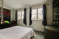 second bedroom with a double bed, shelves fully-stocked with hardbound books, and a desk in a 3-bedr