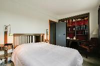 second bedroom with a double bed, shelves fully-stocked with hardbound books, and a desk in a 3-bedr