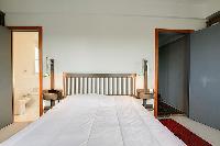 second bedroom with a double bed, shelves fully-stocked with hardbound books, and a desk in a 3-bedr