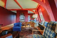 elegant living area with rich red walls, a blue sofa, a matching armchairs, and a few desks in a 3-b