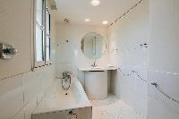an en-suite bathroom with a toilet, a sink, a built-in cabinet, a mirror, and a bathtub in a 3-bedro