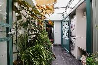 lovely patio with numerous plants illuminated by the skylight in a 3-bedroom Paris luxury apartment