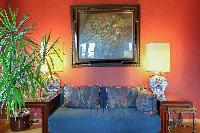 elegant living area with rich red walls, a blue sofa, a matching armchairs, and a few desks in a 3-b