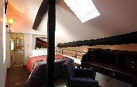 second bedroom at the mezzanine overlooking the living room with double bed, wooden floor, closet, e