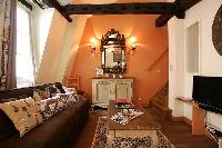 rustic living area with brown sofa, wooden table, cabinet, mirror, and lamps in a  2-bedroom Paris l