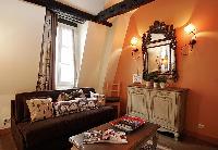 rustic living area with brown sofa, wooden table, cabinet, mirror, and lamps in a  2-bedroom Paris l