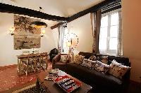 rustic living area with brown sofa, wooden table, cabinet, mirror, and lamps in a  2-bedroom Paris l