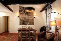 lovely dining area with wooden table and chairs for 4, exposed beams, and paintings in a 2-bedroom P