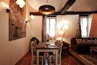 lovely dining area with wooden table and chairs for 4, exposed beams, and paintings in a 2-bedroom P