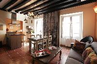 cozy living area, dining area and kitchen with exposed beams in a 2-bedroom Paris luxury apartment