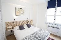 modern bedroom with bedside tables, lamps, and a queen-size bed in a 1-bedroom Paris luxury apartmen
