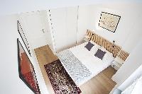 modern bedroom with bedside tables, lamps, and a queen-size bed in a 1-bedroom Paris luxury apartmen