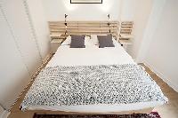 modern bedroom with bedside tables, lamps, and a queen-size bed in a 1-bedroom Paris luxury apartmen