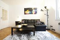cozy living area with a media shelf, a television, a sleek center table, and a large, black sofa bed
