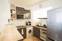 monochromatic and space-efficient kitchen with washer and dryer combo in a 1-bedroom Paris luxury ap