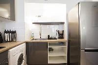 monochromatic and space-efficient kitchen with washer and dryer combo in a 1-bedroom Paris luxury ap