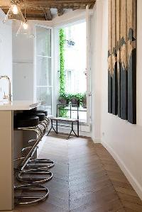 French window with potted plants, breakfast bar and stools in Paris luxury apartment