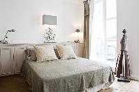 elegant bedroom with built-in cabinets, lamps and queen-size bed in a 2-bedroom Paris luxury apartme