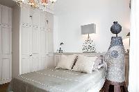 elegant bedroom with built-in cabinets, lamps and queen-size bed in a 2-bedroom Paris luxury apartme