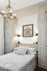 classy bedroom with built-in closets, lamps, and queen-size bed  in Paris luxury apartment