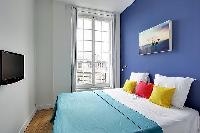 cozy bedroom with a double bed in blue and white hues in a Paris luxury apartment