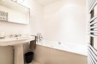 first bathroom with white and beige tiles, furnished with a sink, a toilet, and a bathtub in a 3-bed