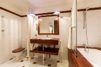 second bathroom with white tiles and wood paneling equipped with a toilet, a sink, and a bathtub in 