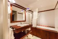 second bathroom with white tiles and wood paneling equipped with a toilet, a sink, and a bathtub in 