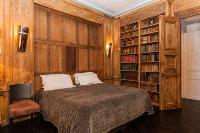 master bedroom with wood paneling and bookshelves with leather-bound books, fireplace, and a desk wi