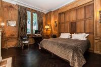 master bedroom with wood paneling and bookshelves with leather-bound books, fireplace, and a desk wi