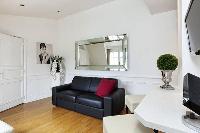 cozy living area with a large black sofa and a chair in a  studio Paris luxury apartment