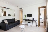 cozy living area with a large black sofa and a chair in a  studio Paris luxury apartment