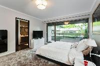 master bedroom fully-equipped with a television, a king-size bed, bedside tables, lamps, and an en-s