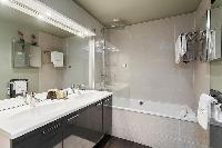 an en-suite bathroom with double sinks, and a bathtub in a 4-bedroom Paris luxury apartment