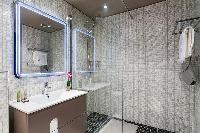 an en-suite bathroom with shower and sink in a 4-bedroom Paris luxury apartment