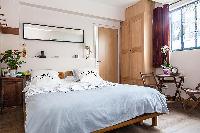 modern bedroom with a queen-size bed, a bedside table, and a mirror in a 1-bedroom Paris luxury apar