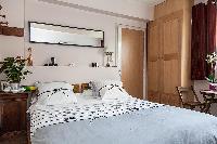 modern bedroom with a queen-size bed, a bedside table, and a mirror in a 1-bedroom Paris luxury apar