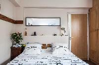 modern bedroom with a queen-size bed, a bedside table, and a mirror in a 1-bedroom Paris luxury apar