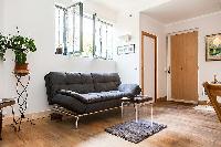 living area with a double sofa bed and potted plants  in a 1-bedroom Paris luxury apartment