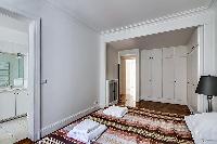 bedroom furnished with queen-size bed,colorful bedspreads, a large dressing area, built-in closets, 