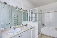 immaculate white en-suite bathrooms fully-furnished with double sink, toilet, mirror, and bathtub wi
