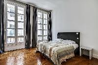 bedroom furnished with queen-size bed and colorful bedspreads  in a 3-bedroom Paris luxury apartment